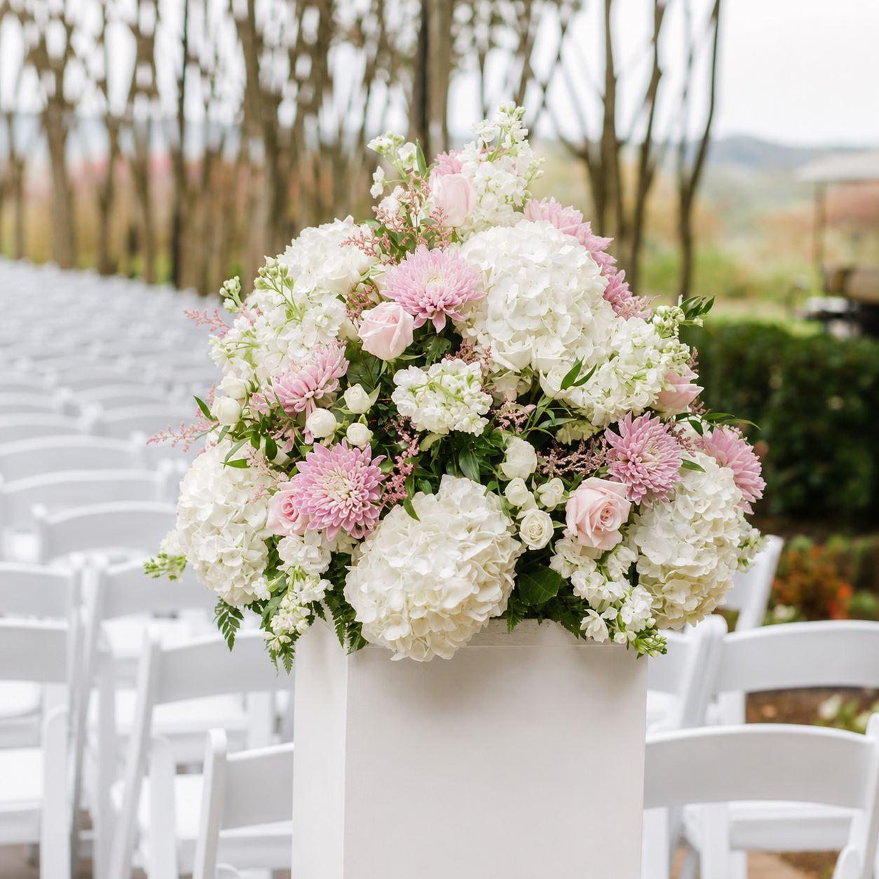White and pink pedestal floral arrangement at outdoor ceremony aisle
